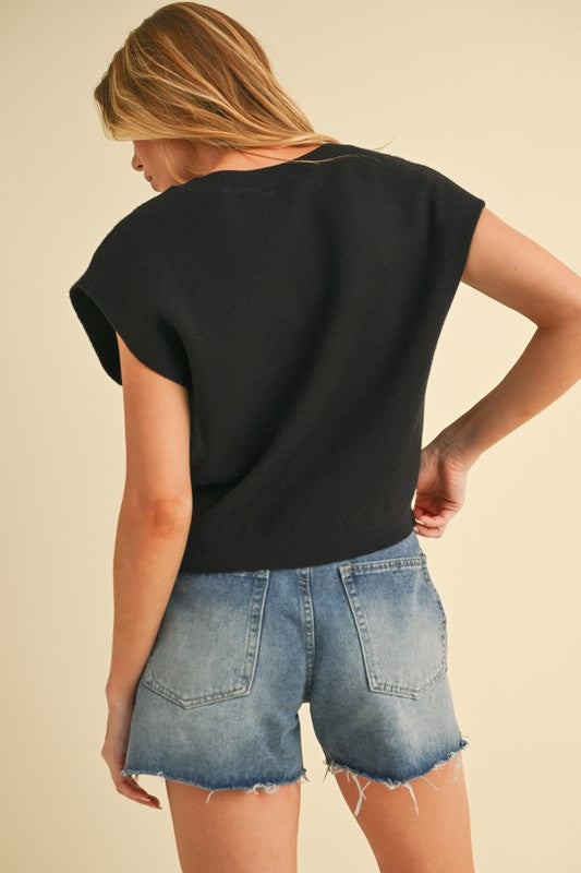 Top negro de tejido knit con mangas cortas y detalle frontal tipo twist.