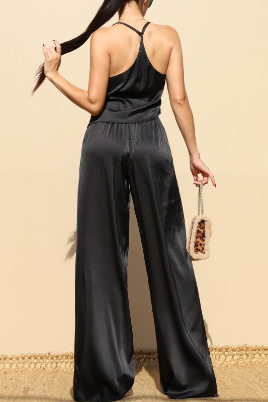 Set negro elegante con top de tirantes ajustables y pantalón ancho con bolsillos.