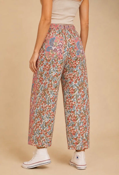 Pantalón de mujer de talle alto y pierna amplia con estampado floral patchwork en tonos rosa, azul y crema, bolsillos delanteros y traseros.