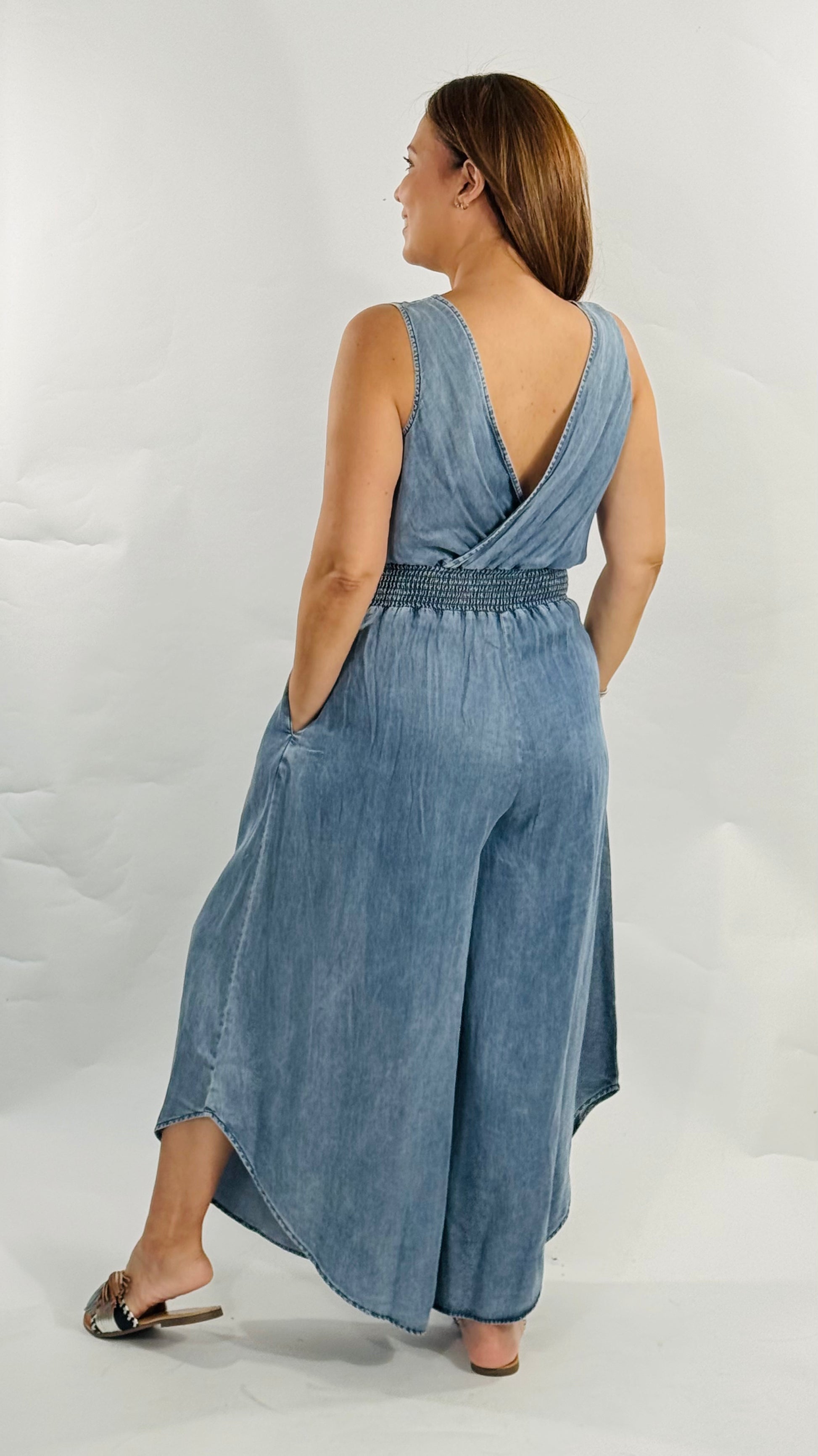 Jumpsuit de pierna ancha con escote cruzado, cintura elástica y bolsillos laterales.