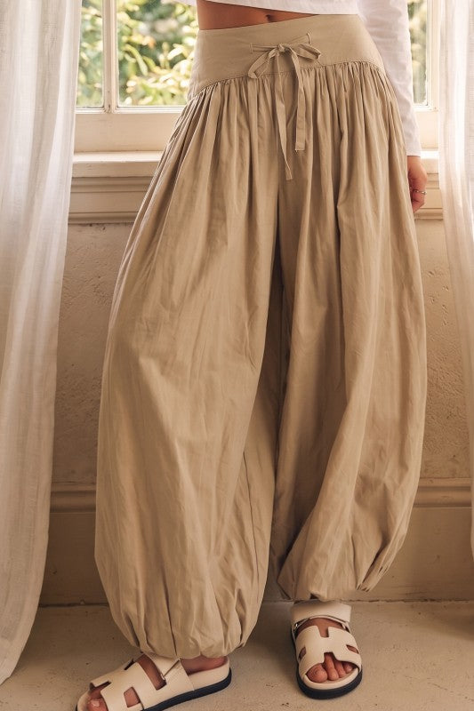 Noelle Barrel Pants color beige con silueta amplia, cintura ajustable con lazo delantero y elástico en el ruedo.