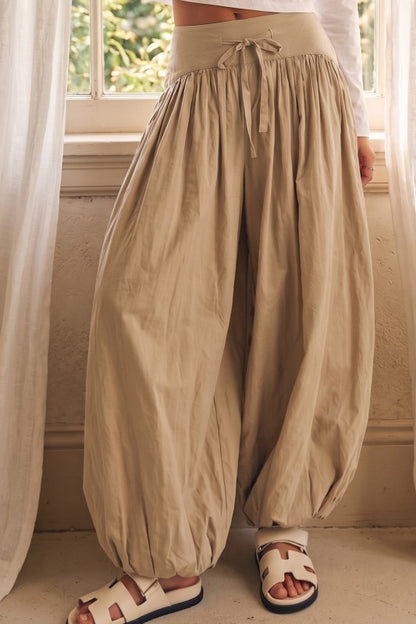 Noelle Barrel Pants color beige con silueta amplia, cintura ajustable con lazo delantero y elástico en el ruedo.