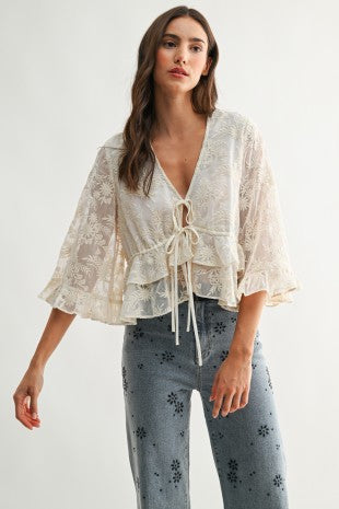 Lace Blouse color crema con bordado floral, lazos ajustables al frente y mangas amplias.