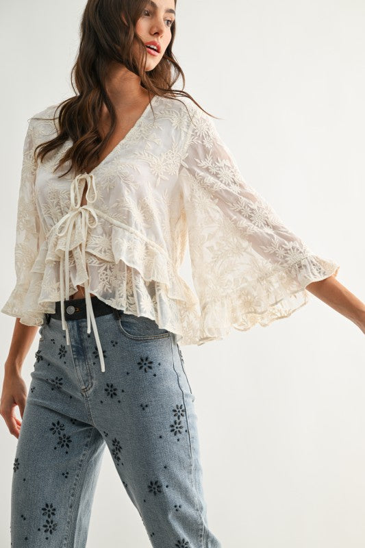 Lace Blouse color crema con bordado floral, lazos ajustables al frente y mangas amplias.