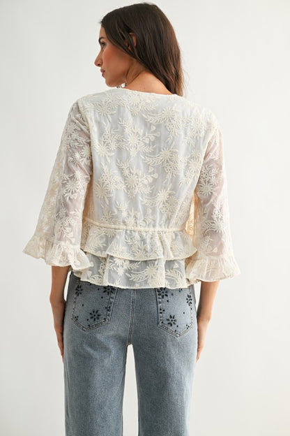 Lace Blouse color crema con bordado floral, lazos ajustables al frente y mangas amplias.