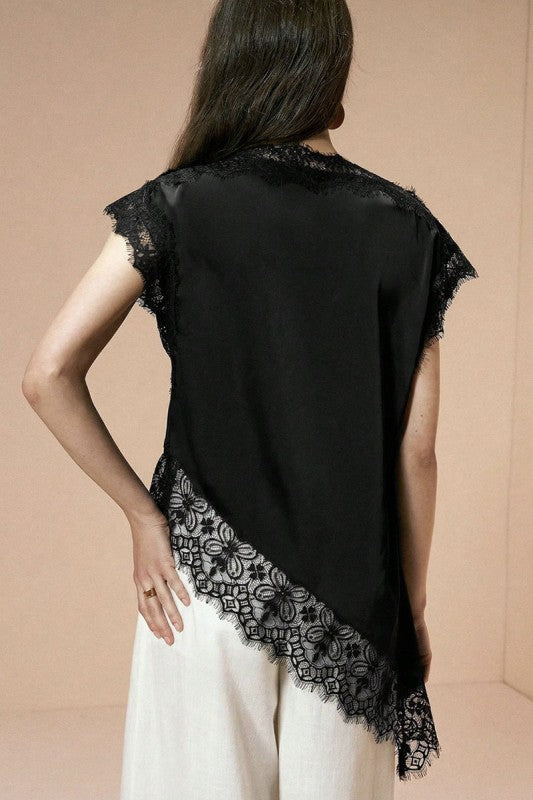 Blusa elegante de mujer color negro con encaje floral en el cuello, mangas y ruedo asimétrico.