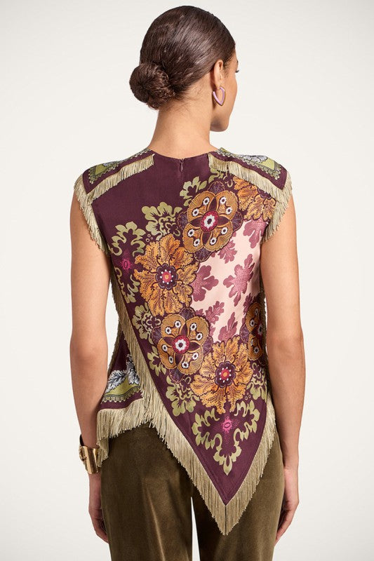 Blusa de mujer con estampado floral en tonos vino, rosa y dorado, flecos decorativos y corte asimétrico.