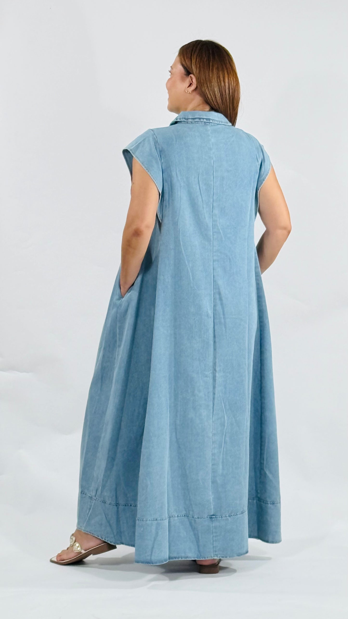 Vestido largo de mahón con botones metálicos decorativos al frente, cuello clásico y bolsillos laterales.