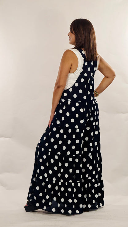 Maxi jumpsuit azul marino con estampado de polka dots blancos, tirantes ajustables, bolsillos funcionales y pantalón de pierna amplia.