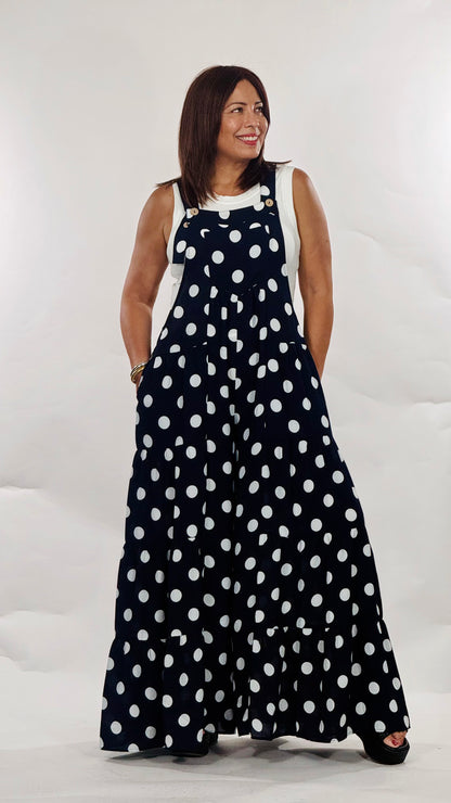 Maxi jumpsuit azul marino con estampado de polka dots blancos, tirantes ajustables, bolsillos funcionales y pantalón de pierna amplia.