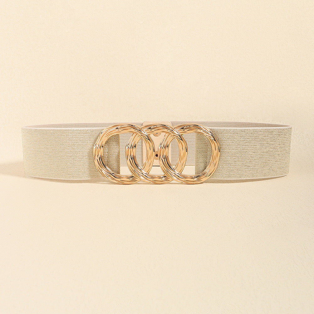 Correa elástica con broche frontal de tres aros metálicos dorados.
