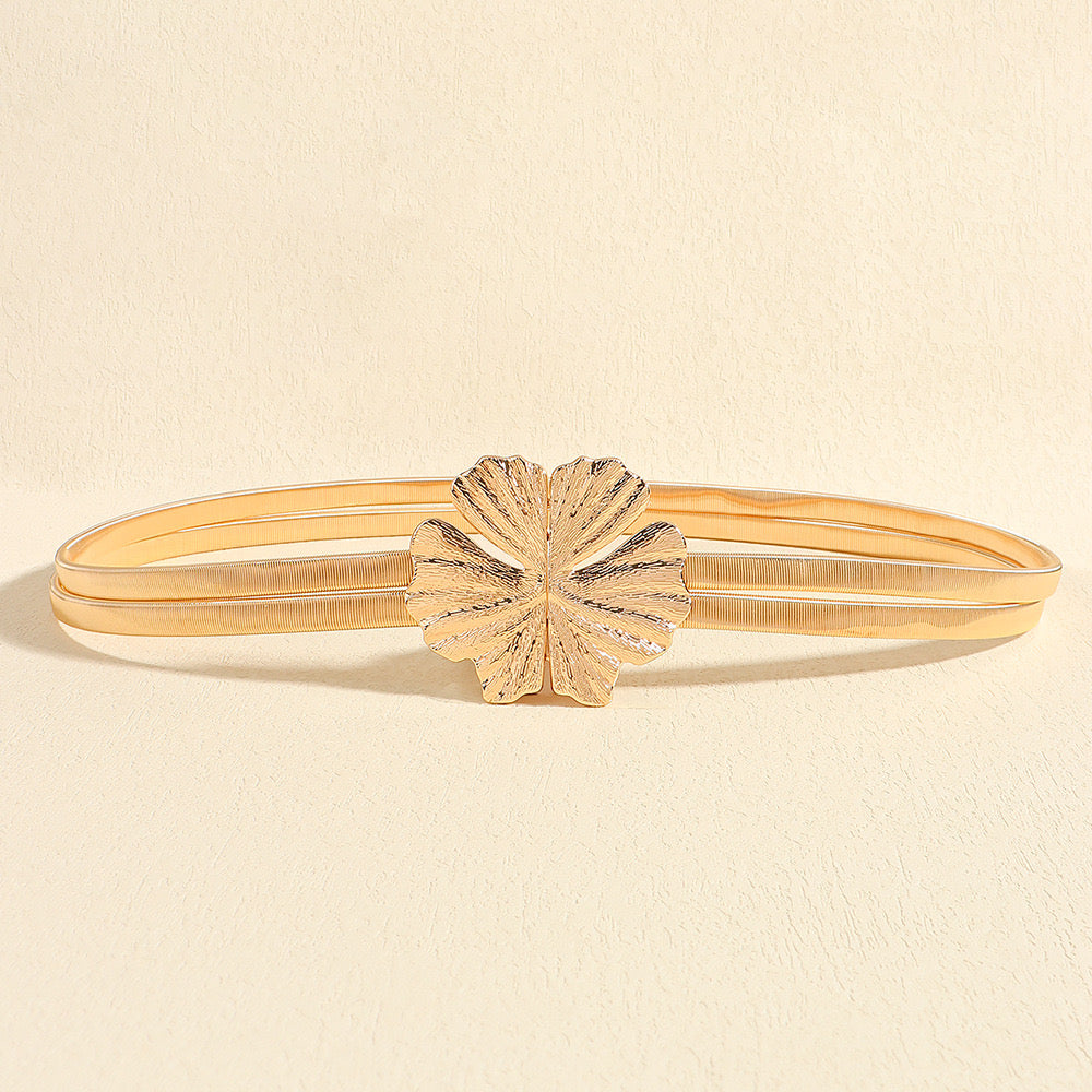 Correa metálica dorada doble con broche frontal en forma de flor texturizada.