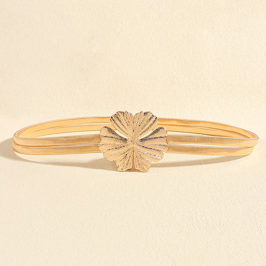 Correa metálica dorada doble con broche frontal en forma de flor texturizada.