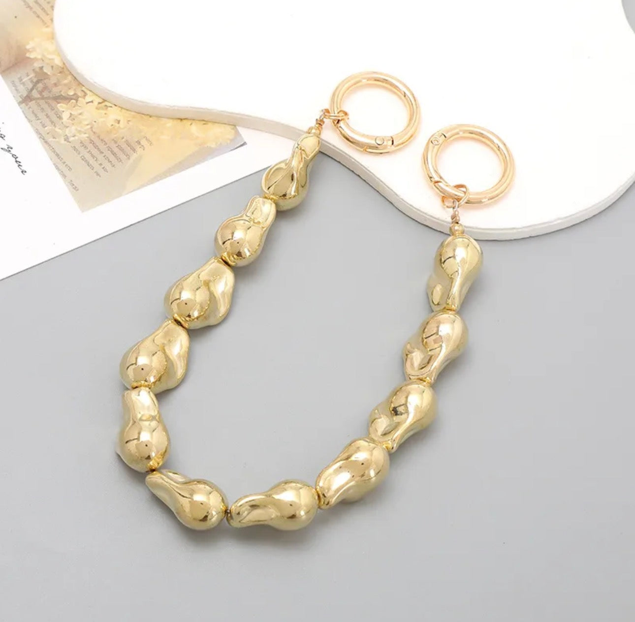 Accesorio tipo chain para celular con diseño de perlas y piezas suaves, ideal para llevar el teléfono en la mano y evitar caídas.