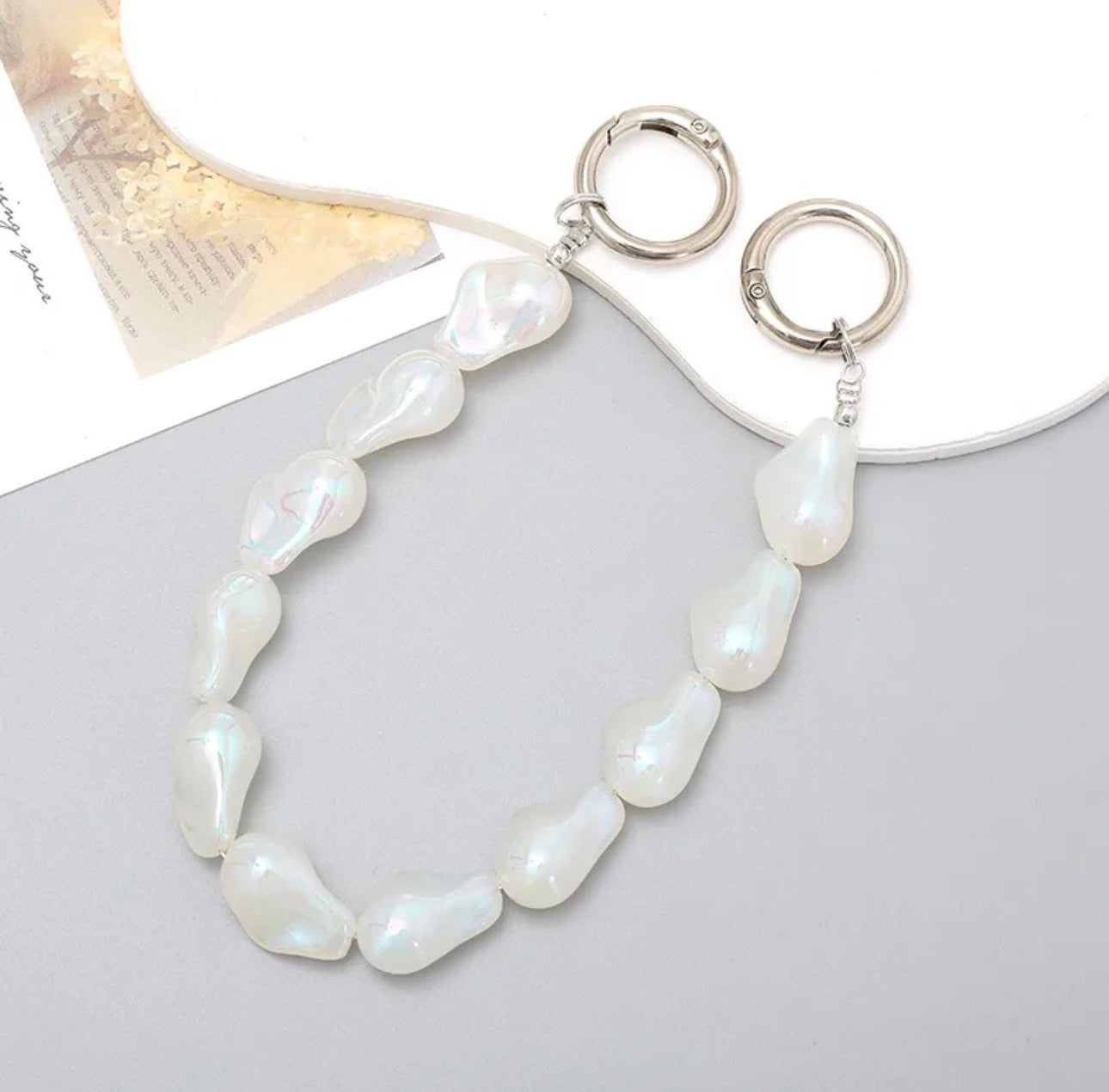 Accesorio tipo chain para celular con diseño de perlas y piezas suaves, ideal para llevar el teléfono en la mano y evitar caídas.