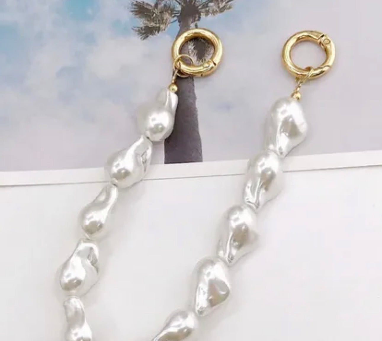 Accesorio tipo chain para celular con diseño de perlas y piezas suaves, ideal para llevar el teléfono en la mano y evitar caídas.