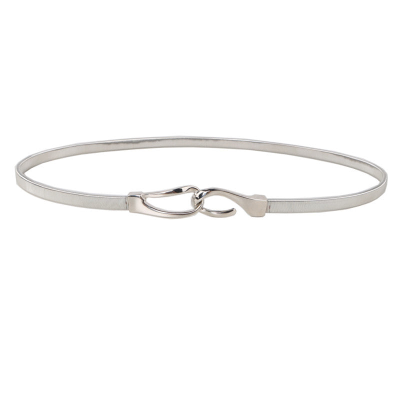 Correa elástica metálica con broche frontal tipo gancho, ideal para definir la cintura y complementar outfits elegantes o casuales.
