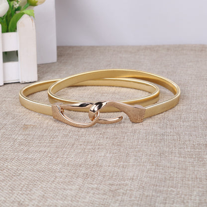 Correa elástica metálica con broche frontal tipo gancho, ideal para definir la cintura y complementar outfits elegantes o casuales.
