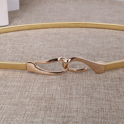 Correa elástica metálica con broche frontal tipo gancho, ideal para definir la cintura y complementar outfits elegantes o casuales.
