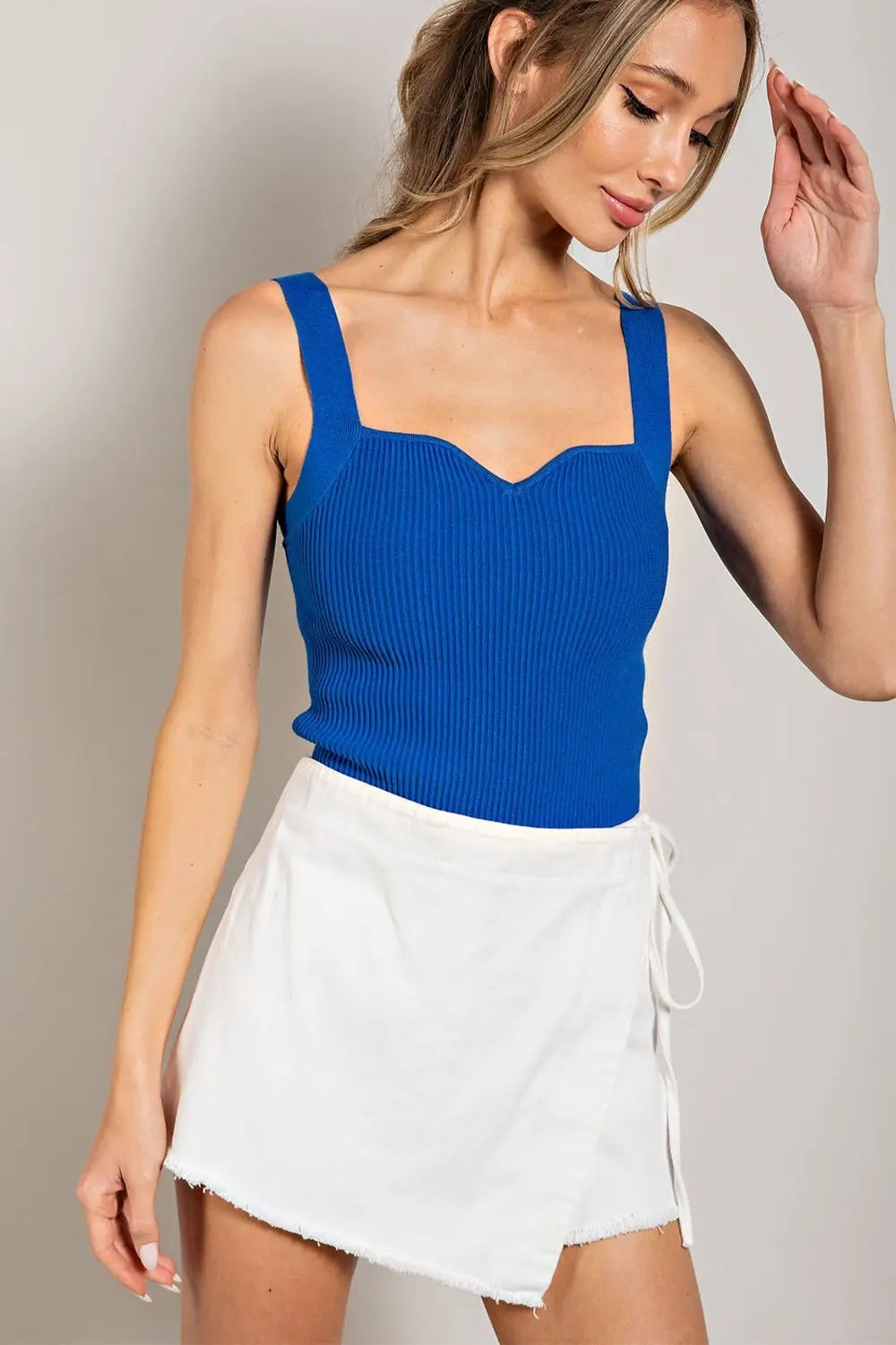 Top básico tejido estilo ribbed con tirantes anchos y escote corazón suave. Diseño ajustado y cómodo ideal para combinar con mahones, faldas o pantalones casuales.