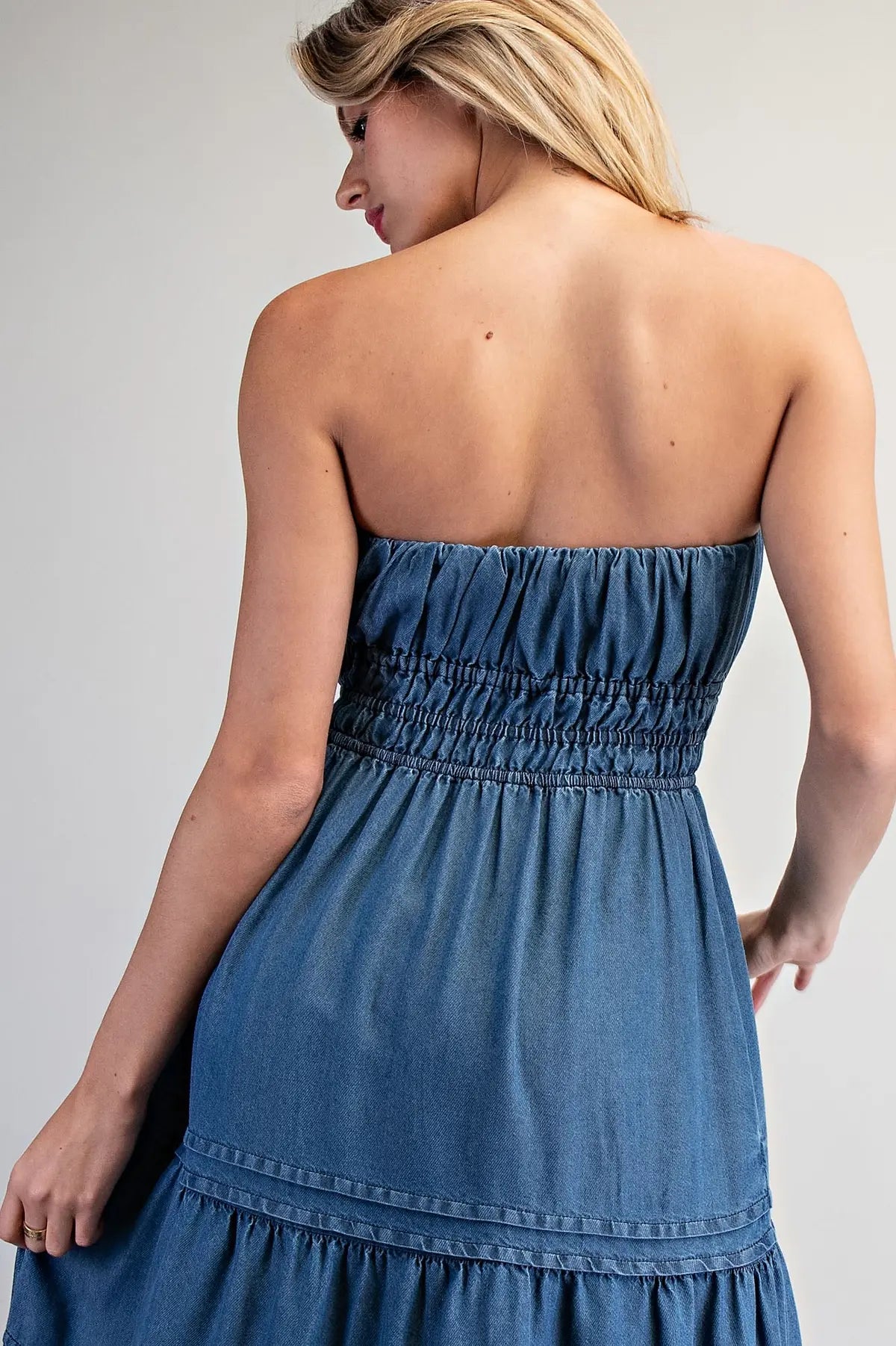 Vestido largo strapless en tela tipo mahón liviana con elástico en el busto, falda en niveles y bolsillos funcionales.