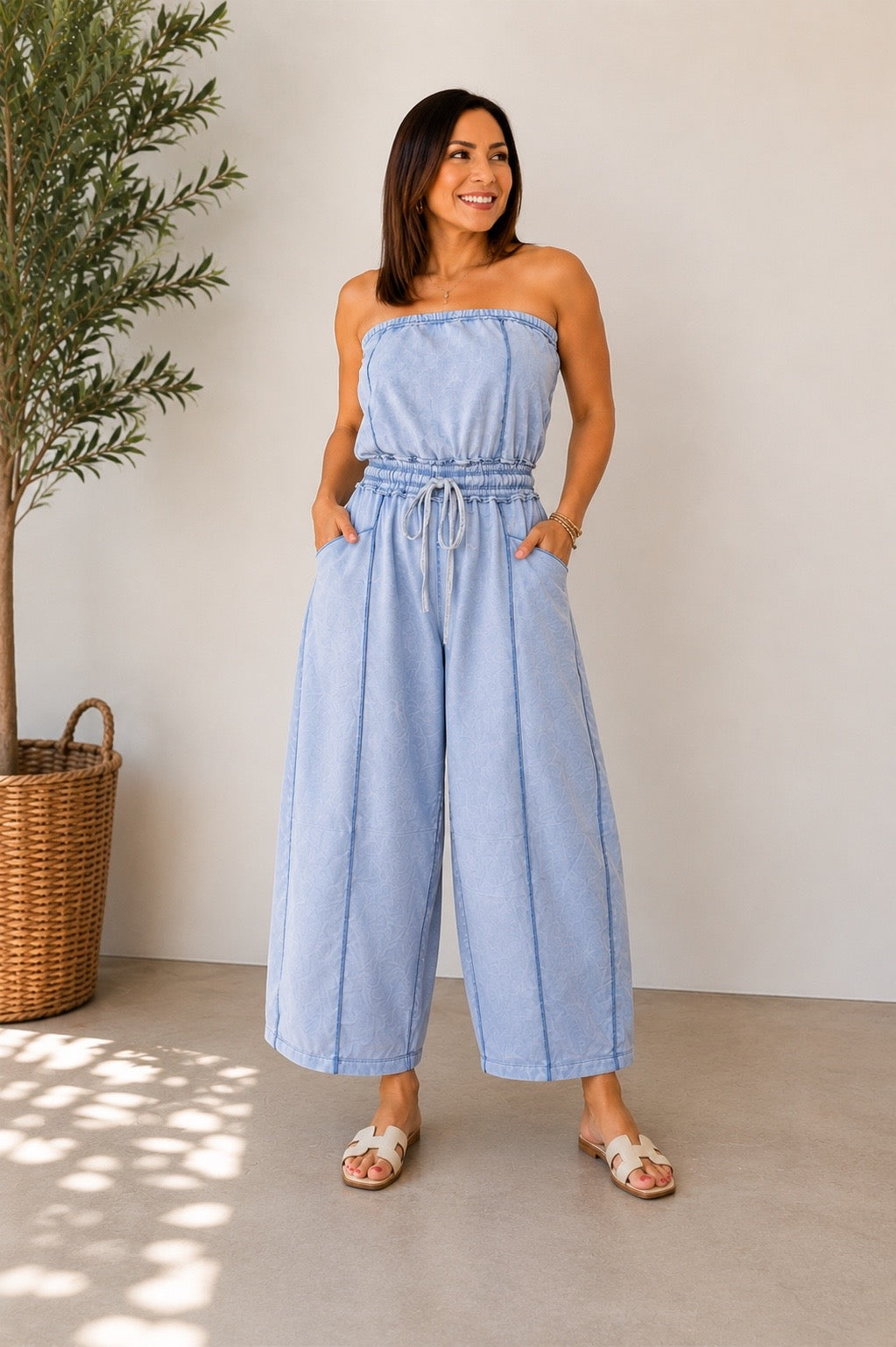 Jumpsuit strapless azul claro con cintura ajustable, bolsillos funcionales y pantalón estilo barrel de ajuste cómodo.