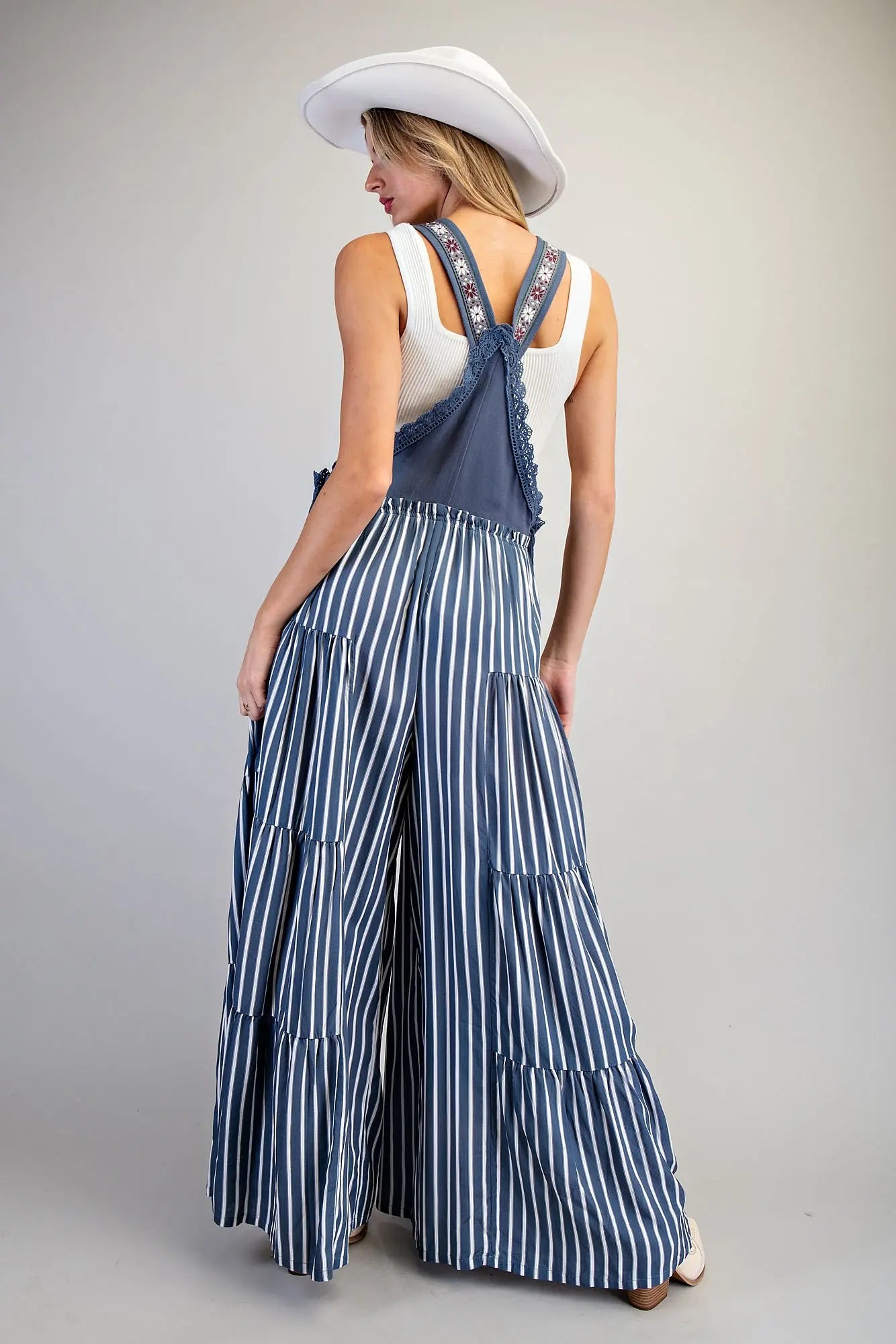 Overall jumpsuit azul con tirantes bordados y pierna ancha de caída fluida.
