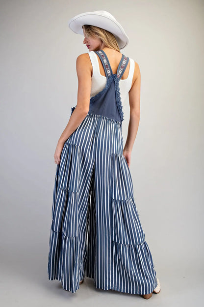 Overall jumpsuit azul con tirantes bordados y pierna ancha de caída fluida.