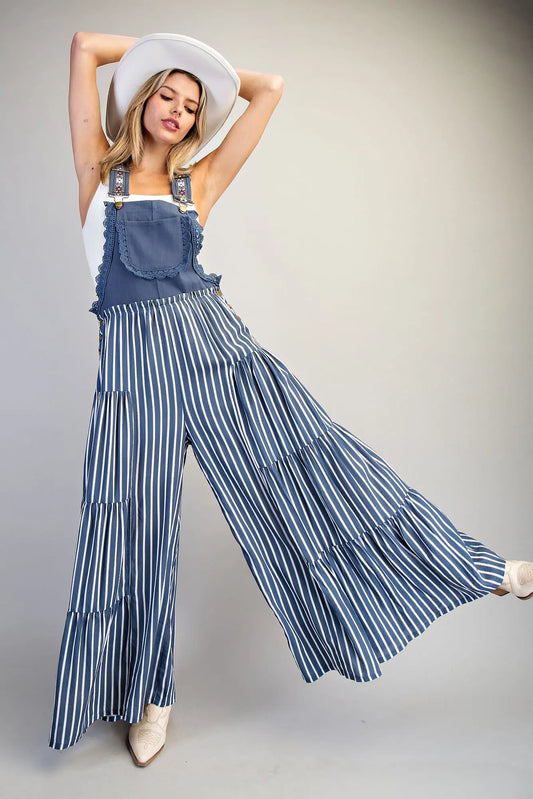 Overall jumpsuit azul con tirantes bordados y pierna ancha de caída fluida.