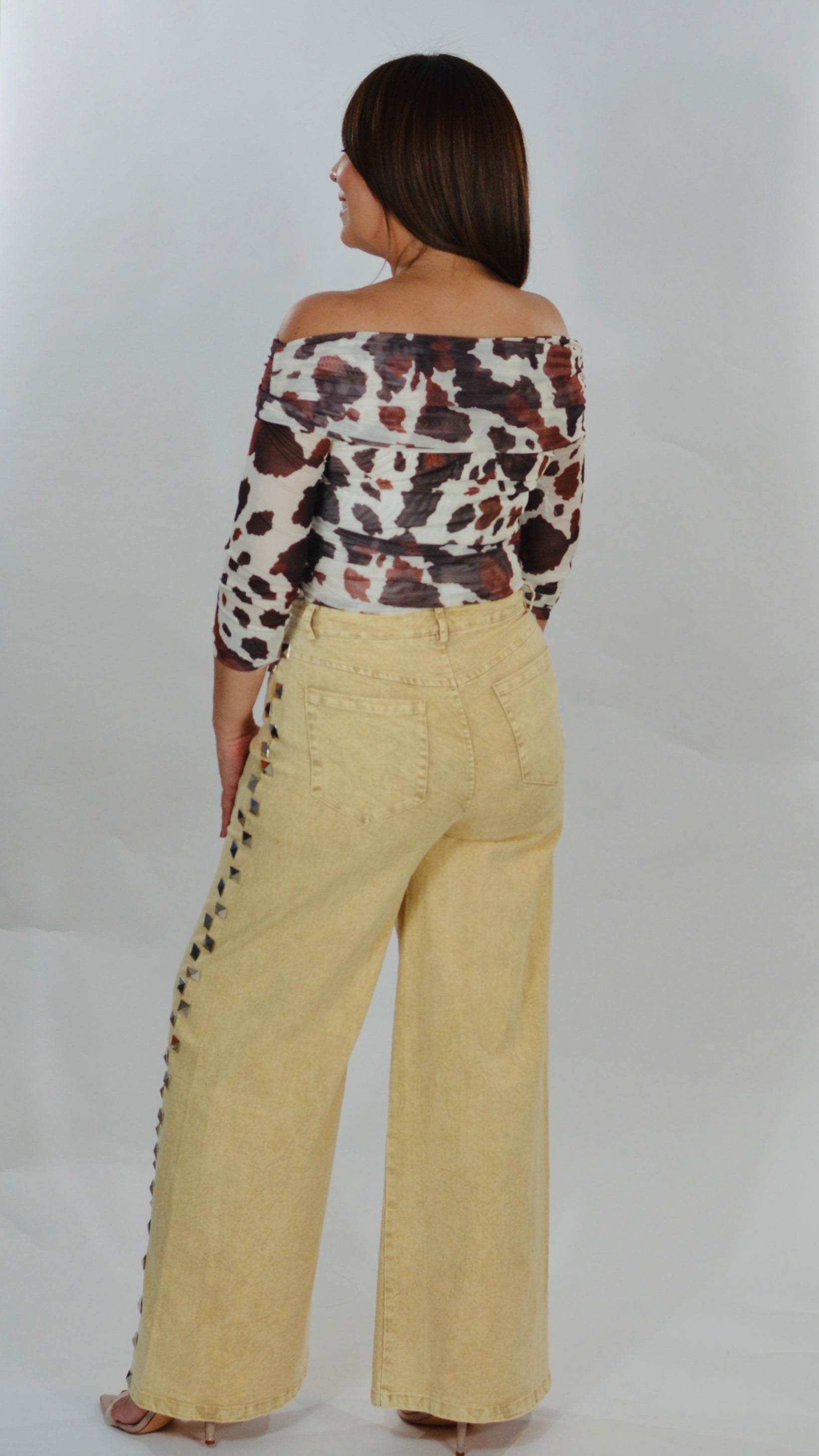 Mahón beige de pierna ancha con detalles metálicos laterales.