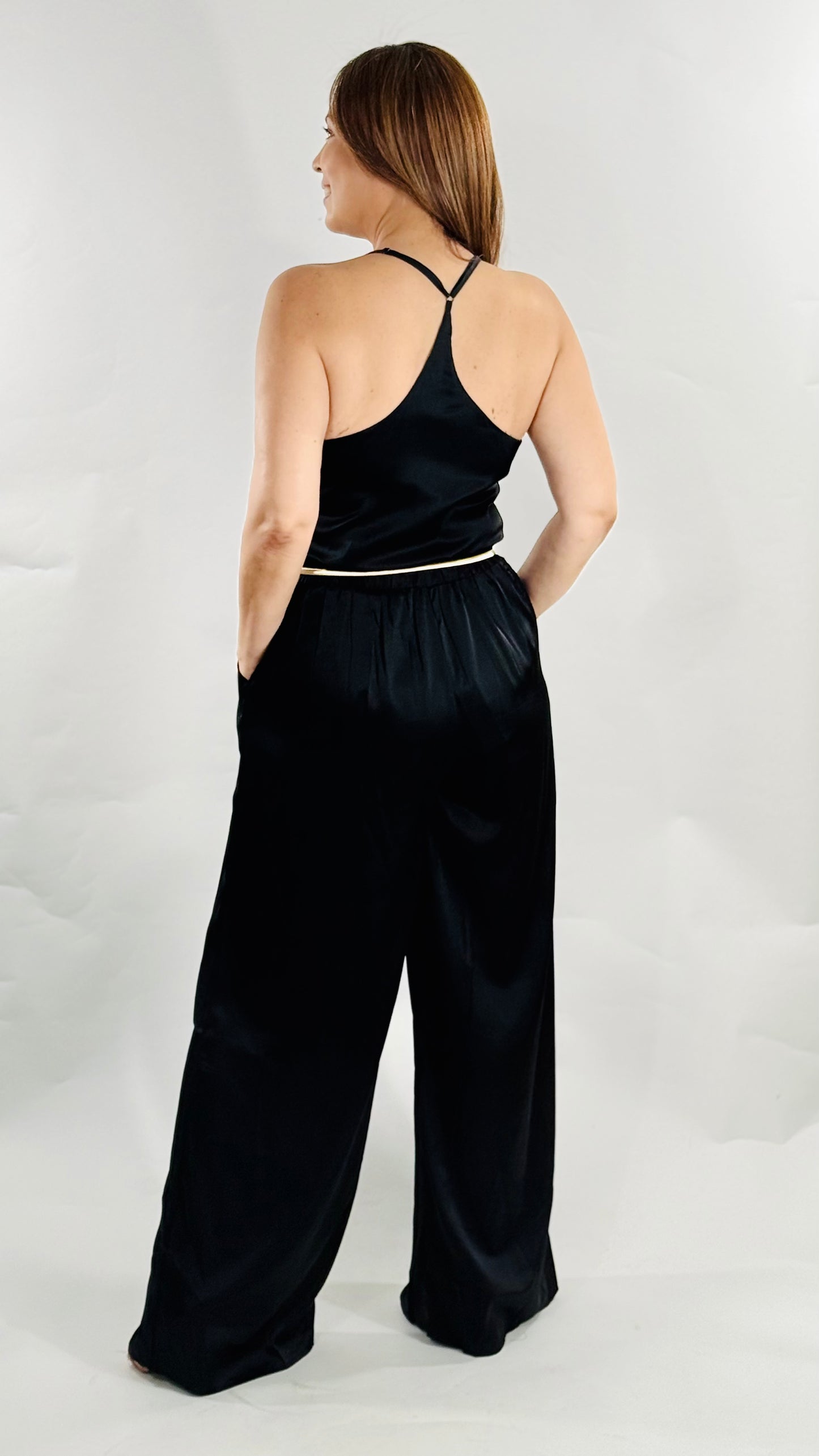 et negro elegante con top de tirantes ajustables y pantalón ancho con bolsillos.