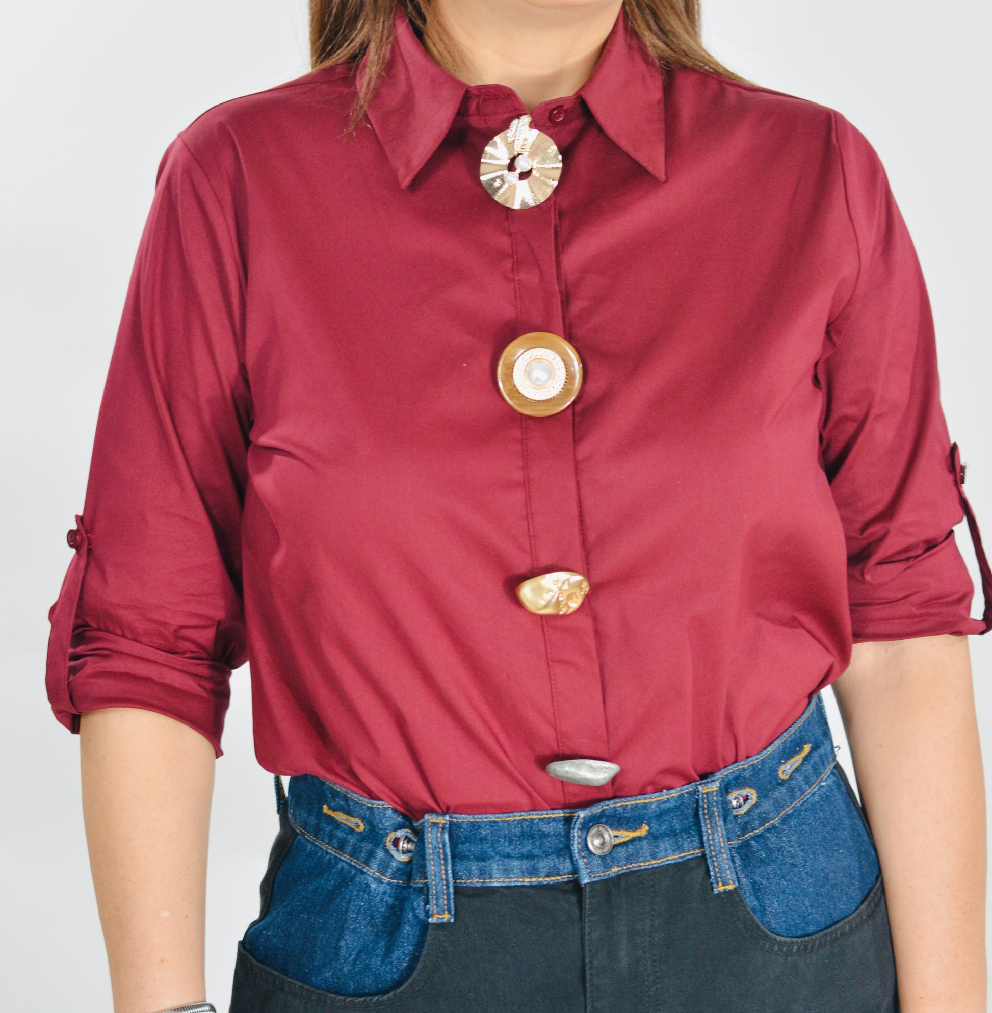 Blusa color vino con botones decorativos y mangas ajustables.